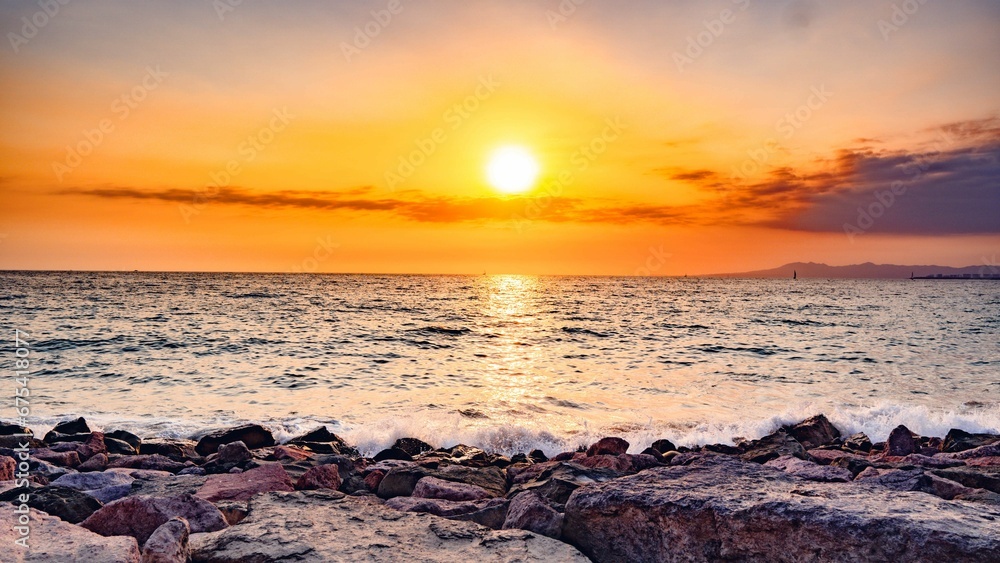 Vibrant sunset sky glows over a picturesque rocky beach