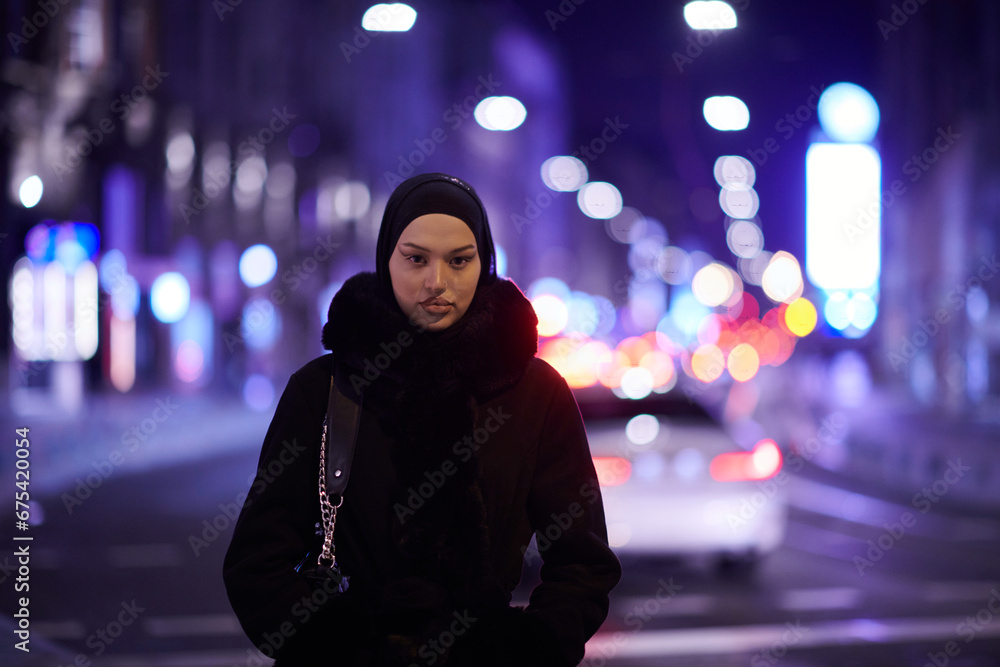 Muslim woman walking on an urban city street on a cold winter night wearing hijab Muslim woman walking on an urban city street on a cold winter night wearing hijab