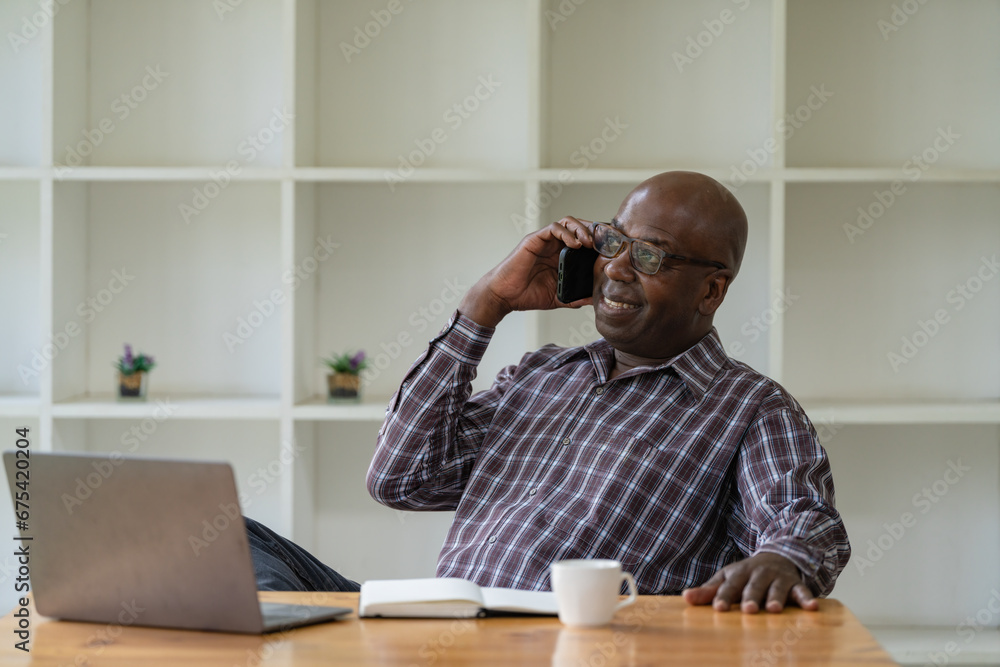 A senior black man using a smartphone in an office. A senior black man using a smartphone in an office.
