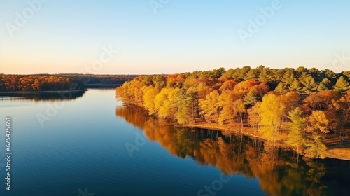 Landscape: A lake surrounded by trees with orange-yellow leaves during sunset.