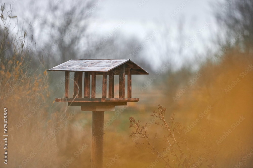 Naklejka premium Handmade wooden bird feeder. Bird feeder made of plywood standing on a post.