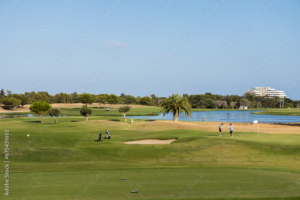 Golf club Terramar in Sitges at sunny day, playing golf on the green grass with water pond, open and green golf course 