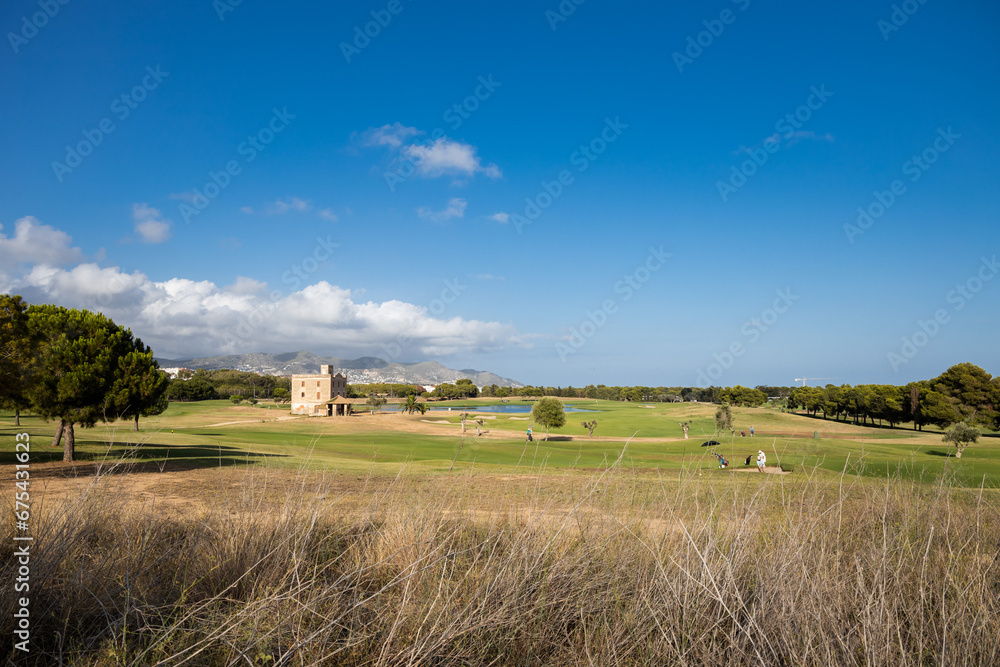 Golf club Terramar in Sitges at sunny day, playing golf on the green grass with water pond, open and green golf course 
