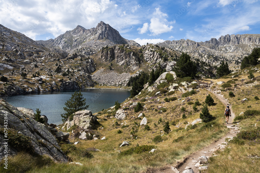 Hiker in a beautiful landscape of the natural park of Aigestortes y Estany de Sant Maurici, Pyrenees valley with river and lake