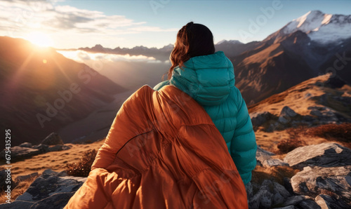 Woman adventurer holding sleeping bag at campground during sundown in mountain range photo