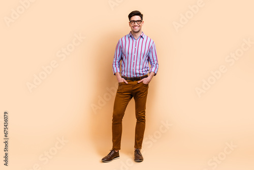 Full length photo of handsome groomed man dressed nice outfit hold hands in pockets isolated on beige color background