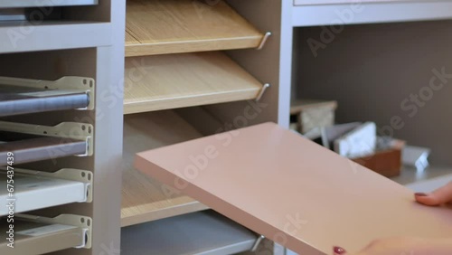 Women's hands and samples of laminated chipboard decors in the store external color palette and textures. The choice of material for new furniture.