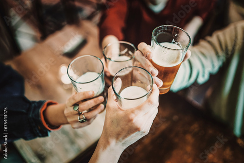 Close-up of a cheerful group of friends toasting with glasses of beer and milk, enjoying a social moment together. photo