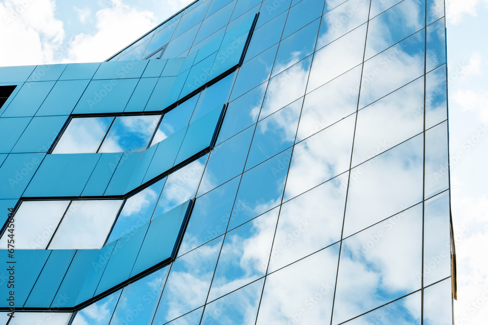 modern facade of glass and steel with reflections. Abstract or graphic photo of the sky with clouds seeming to continue into a building with reflective squares of glass modern facade of glass and steel with reflections. Abstract or graphic photo of the sky with clouds seeming to continue into a building with reflective squares of glass