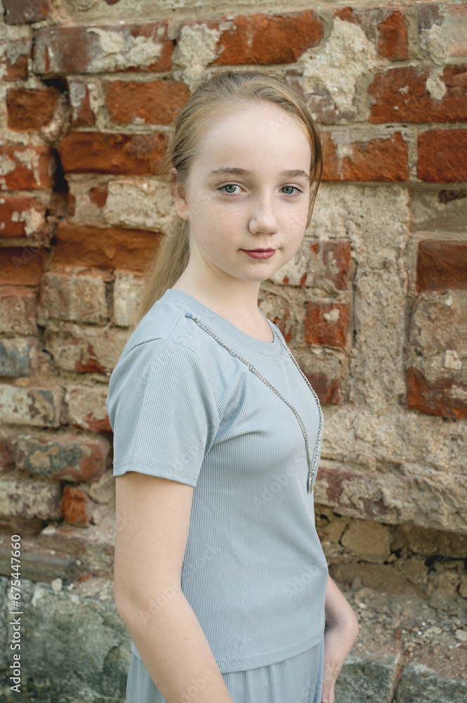 Close up portrait of a beautiful blonde girl with braids against a brick wall. Serious girl of 13-15 years old looking at the camera Close up portrait of a beautiful blonde girl with braids against a brick wall. Serious girl of 13-15 years old looking at the camera