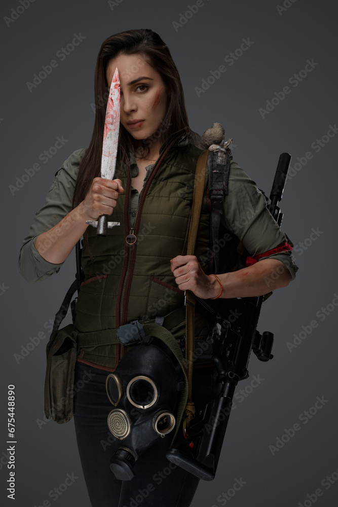 Middle Eastern descent in post-apocalyptic survival gear, brandishing a dagger on a gray backdrop, showcasing her determination to survive Middle Eastern descent in post-apocalyptic survival gear, brandishing a dagger on a gray backdrop, showcasing her determination to survive