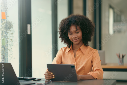 Young African American businesswoman sitting working using tablet in modern office.