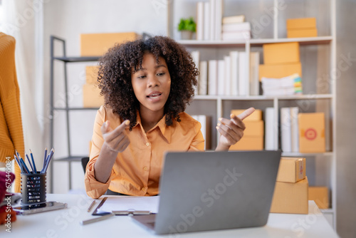 Young African American business owner is video calling with a customer about a product using a laptop computer.