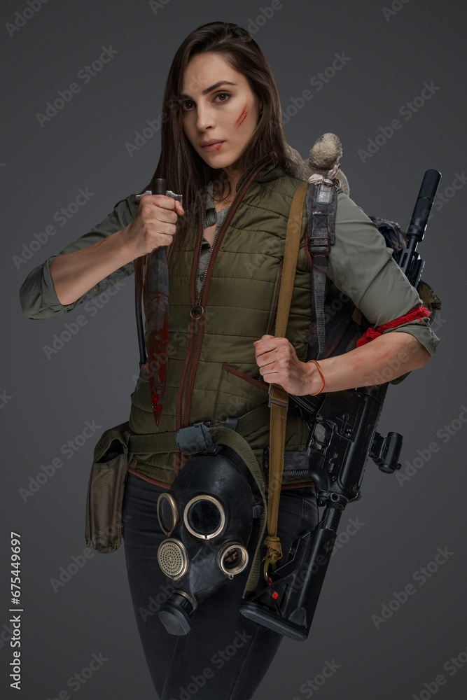 Middle Eastern descent in post-apocalyptic survival gear, brandishing a dagger on a gray backdrop, showcasing her determination to survive Middle Eastern descent in post-apocalyptic survival gear, brandishing a dagger on a gray backdrop, showcasing her determination to survive