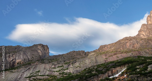 Scenic minimalist panoramic landscape with white clouds in blue sky over rock. Simple minimalism with white clouds in blue sky. Colorful sky scenery. Atmospheric day cloudscape.