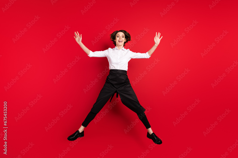 Full length photo of positive excited young woman jump up star shape smile isolated on red color background