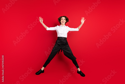 Full length photo of positive excited young woman jump up star shape smile isolated on red color background