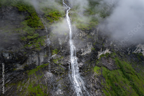 Aerial view of waterfall flowing down cliff into Fjord in Norway