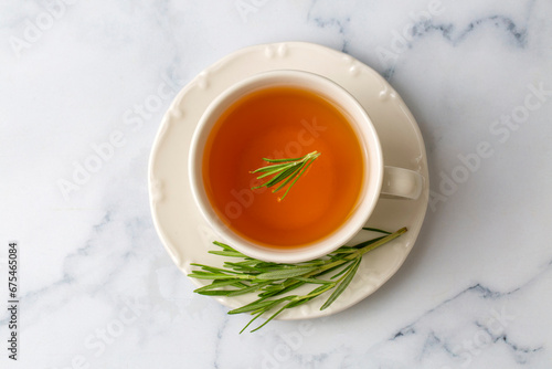 Cup of healthy rosemary tea with fresh rosemary bunch on rustic background, winter herbal hot drink concept, salvia rosmarinus photo