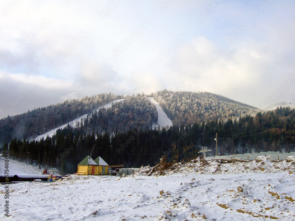 A view of the small houses of the ski resort and ski slopes on another mountain