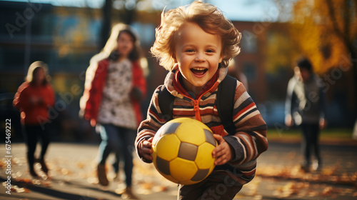 Photo of a smiling child at a school stadium playing football with other children.