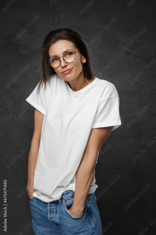 Portrait of an attractive woman in glasses and a white t-shirt against a dark background