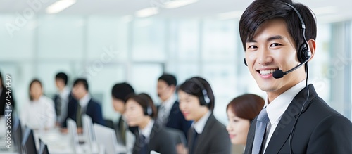 In a bustling Japanese call center the adult Japanese teller efficiently handles business calls wearing a headset with a microphone showcasing their professionalism while providing excellen photo