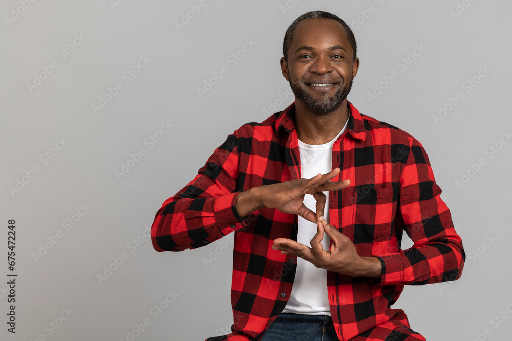 Cheerful black bearded man wearing red checkered shirt showing deaf-mute gestures Cheerful black bearded man wearing red checkered shirt showing deaf-mute gestures