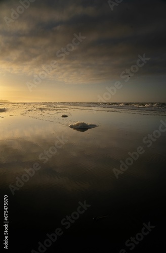 Vertical shot of reflective shallow waters of a beach at sunset