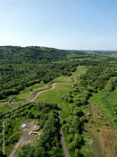 a green grassy field with a river and hills in the distance