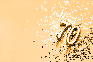 70 years celebration festive background made with golden candles in the form of number Seventy lying on sparkles. Universal holiday banner with copy space.