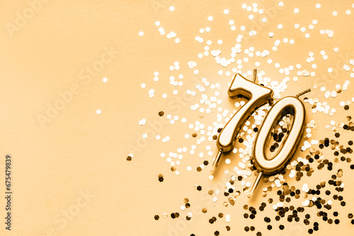 70 years celebration festive background made with golden candles in the form of number Seventy lying on sparkles. Universal holiday banner with copy space.