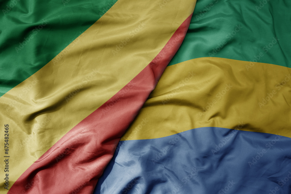 big waving national colorful flag of republic of the congo and national flag of gabon .