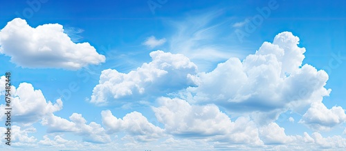 The bright blue sky on a summer day adorned with fluffy white clouds adds to the beauty of nature s backgrounds and showcases the contrasting overcast weather outdoors