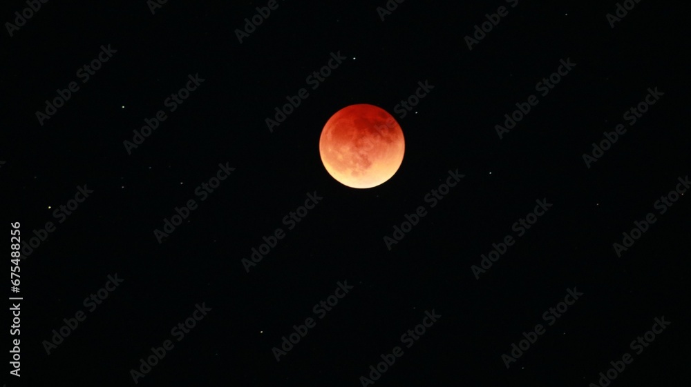Blood-red eclipse of the moon in the night sky with shining stars Blood-red eclipse of the moon in the night sky with shining stars