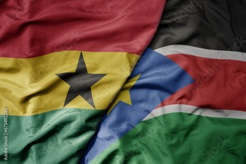 big waving national colorful flag of ghana and national flag of south sudan .