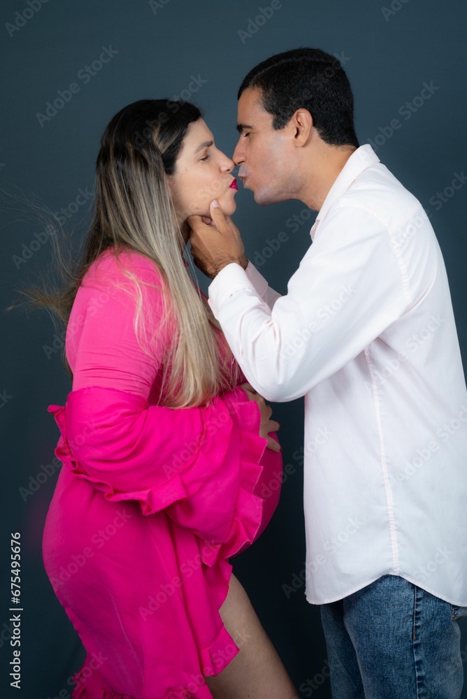 Happy pregnant couple embracing and sharing a romantic kiss Happy pregnant couple embracing and sharing a romantic kiss