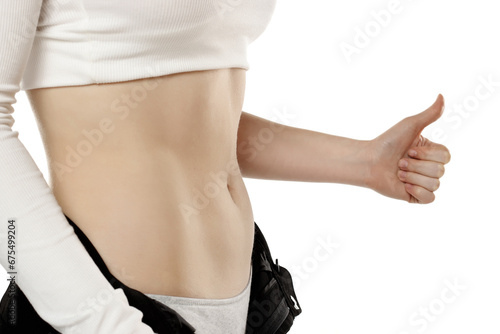 Fit woman showing flat belly and showing thumbs up on a white background. Closeup.