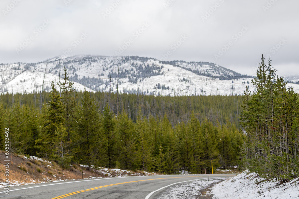 snow on road in the yellowstone mountains, Image shows the first signs of snowfall in Yellowstone national park with the forest and mountain background, October 2023 snow on road in the yellowstone mountains, Image shows the first signs of snowfall in Yellowstone national park with the forest and mountain background, October 2023