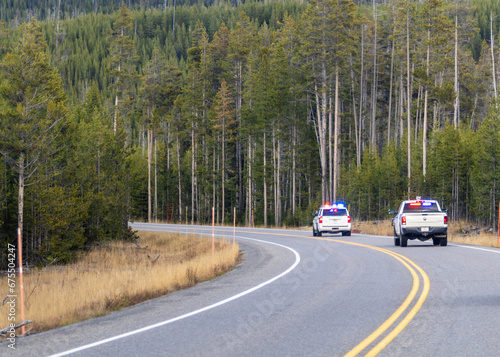 Park rangers driving through Yellowstone national park with blue and red emergency lights on