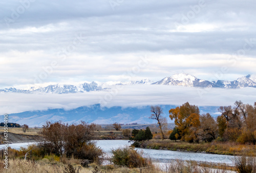 River view with low level cloud and snow covered mountains on the outskirts of Yellowstone national park on a cold autumn's day