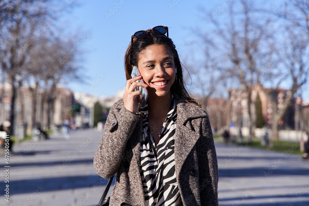 young latina woman talking on smartphone walking in the city. young latina woman talking on smartphone walking in the city.