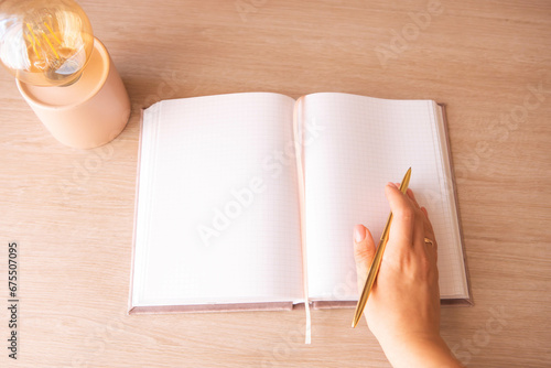 female hand holding a pen on a notepad