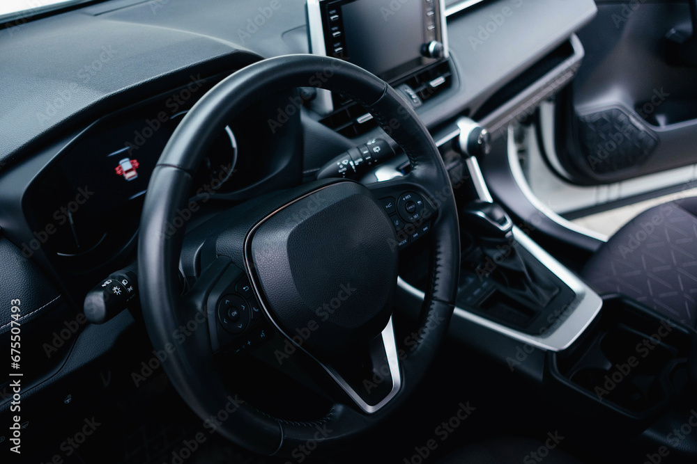 Modern black car interior, leather steering wheel, climate control, navigation, air ducts, deflectors on the car panel. Details interior. Modern black car interior, leather steering wheel, climate control, navigation, air ducts, deflectors on the car panel. Details interior.