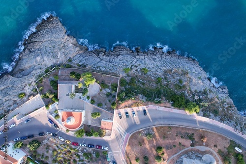 Aerial view above of a small lighthouse by the rocky coastline in Oropesa, Spain. photo