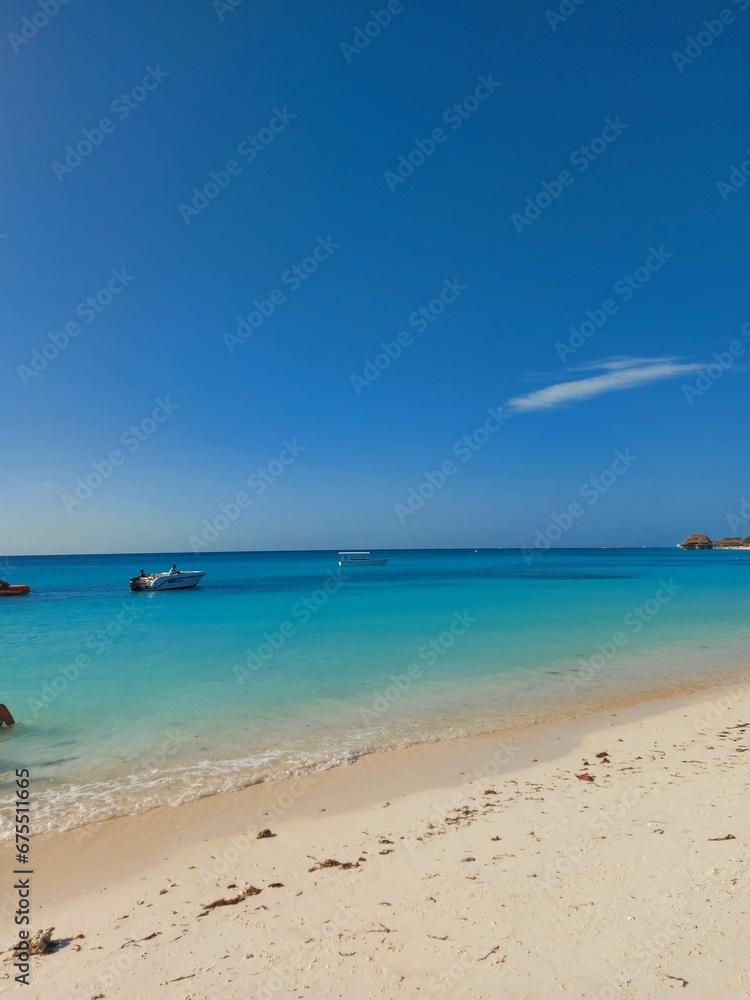 Beach scene with an idyllic island with several boats in the background in Tanzania, Zanzibar