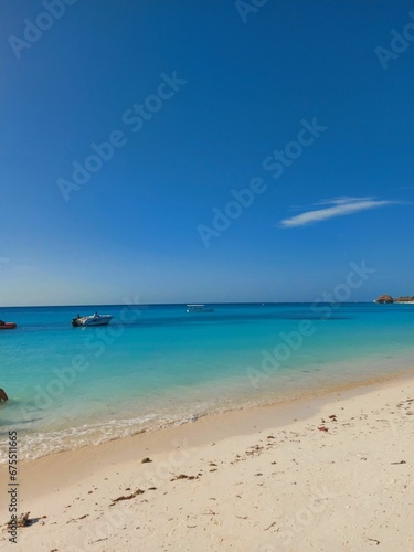 Beach scene with an idyllic island with several boats in the background in Tanzania  Zanzibar
