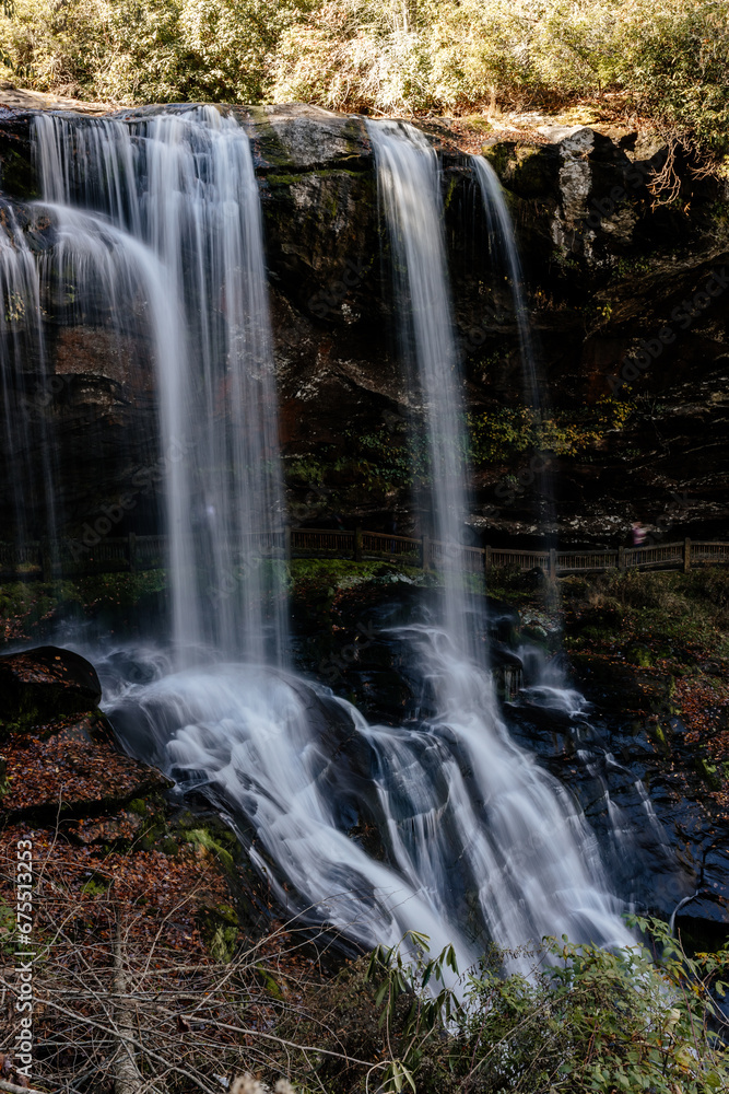 Obraz premium Beautiful high waterfall in fall. Landscape with a mountain river and a waterfall on a sunny autumn day. Dry Falls in Nantahala National Forest, Highlands, North Carolina, USA