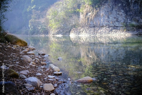 Tranquil river with large rocks in the foreground and lush greenery in Shaoxing, China photo