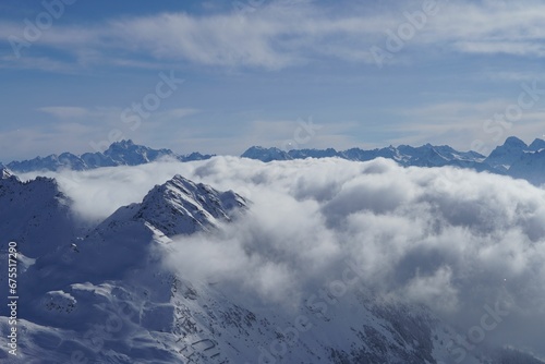 Stunning aerial view of clouds covering snow-capped mountains.
